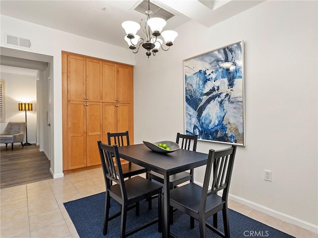 dining space with light tile patterned floors, visible vents, and an inviting chandelier