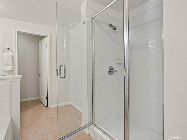 bathroom with baseboards, a shower stall, and tile patterned flooring
