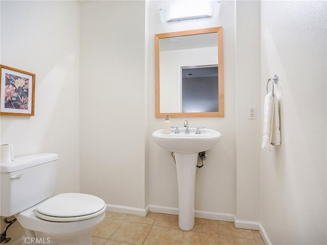 bathroom featuring a sink, tile patterned floors, baseboards, and toilet
