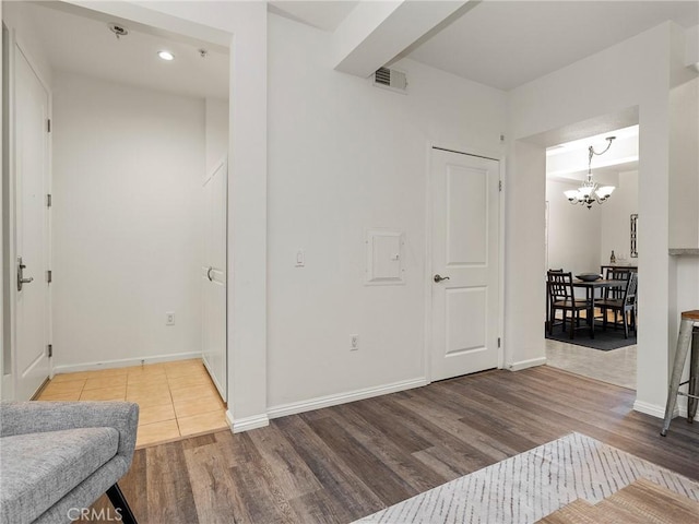 foyer entrance featuring baseboards, visible vents, an inviting chandelier, and wood finished floors