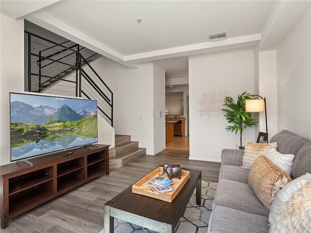 living area featuring stairway, wood finished floors, and visible vents