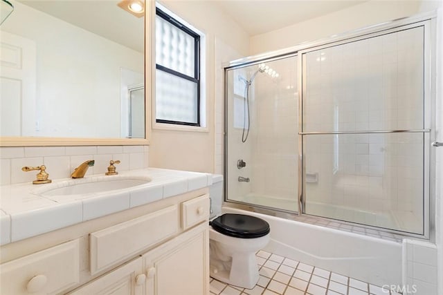 bathroom featuring tile patterned flooring, combined bath / shower with glass door, toilet, and vanity