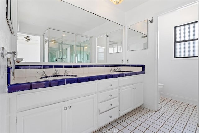 full bath featuring double vanity, a stall shower, a sink, tile patterned floors, and toilet