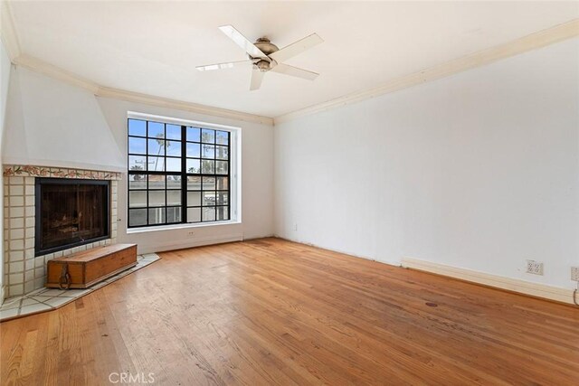 unfurnished living room with crown molding, a fireplace with flush hearth, a ceiling fan, and wood finished floors