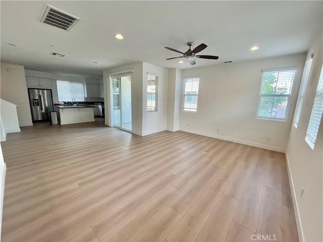 unfurnished living room featuring a healthy amount of sunlight, baseboards, and visible vents