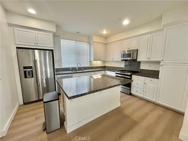 kitchen with white cabinets, stainless steel appliances, a sink, and light wood-style floors