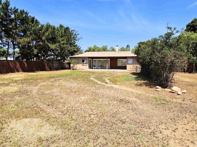rear view of house featuring fence and a lawn