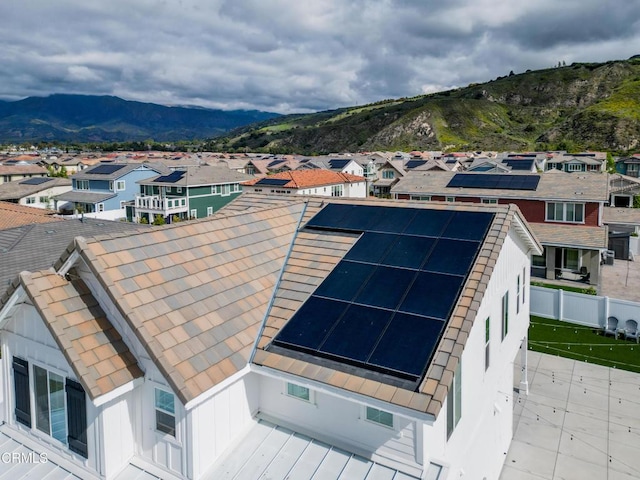 exterior space featuring a residential view, a mountain view, board and batten siding, and solar panels
