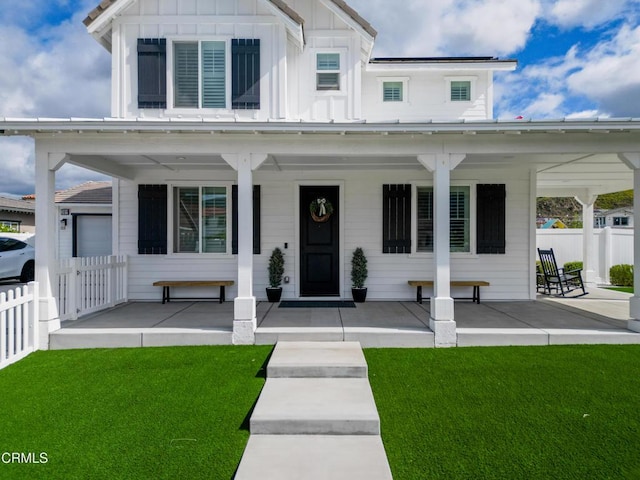 modern inspired farmhouse with a porch, fence, and a front lawn