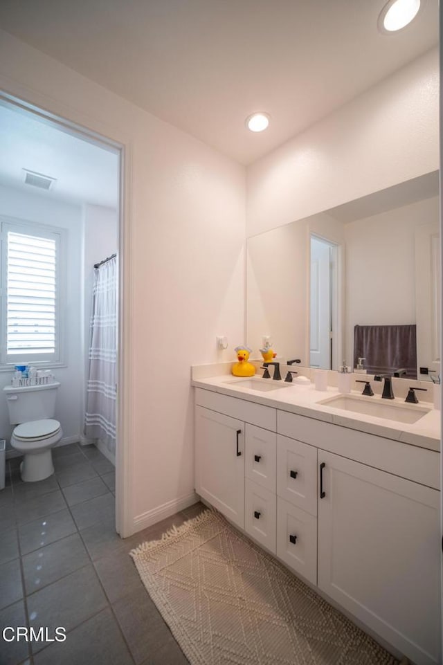bathroom featuring visible vents, vanity, toilet, baseboards, and tile patterned floors