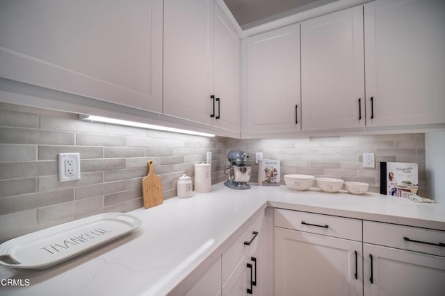 kitchen featuring white cabinetry, light stone countertops, and tasteful backsplash