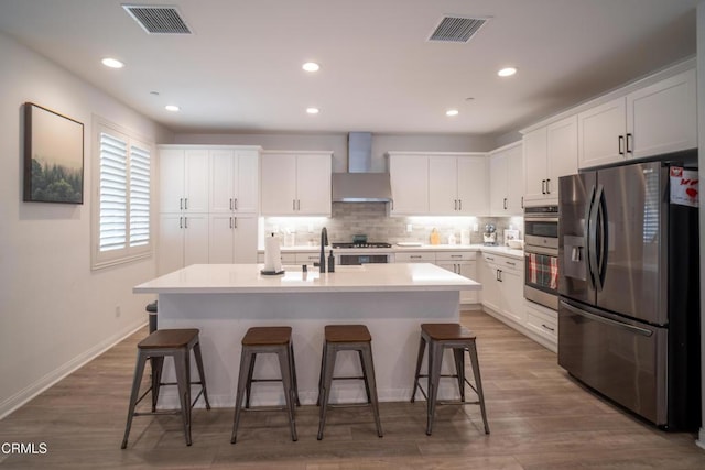 kitchen with white cabinets, visible vents, appliances with stainless steel finishes, and wall chimney exhaust hood