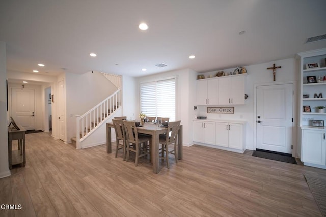 dining space with light wood-style floors, stairs, and visible vents