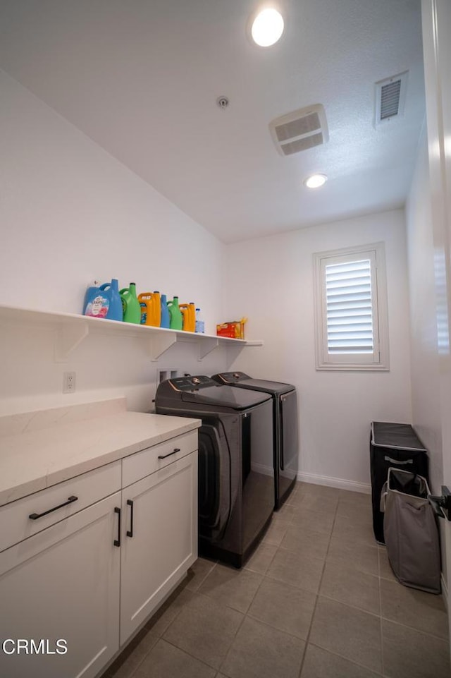 washroom with cabinet space, light tile patterned floors, visible vents, and washer and clothes dryer
