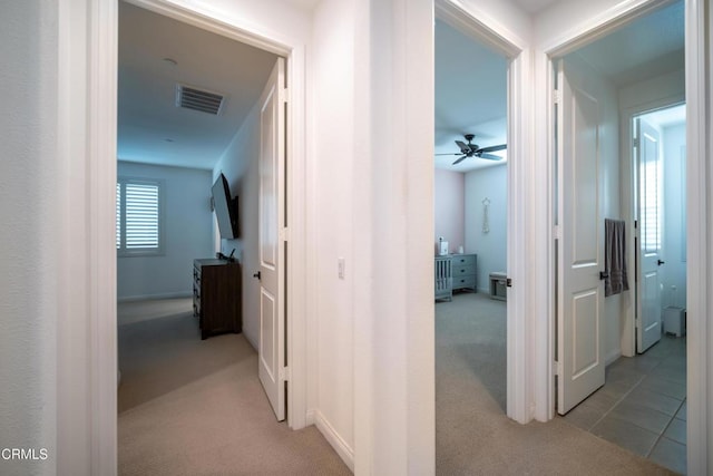 hall with visible vents and light colored carpet
