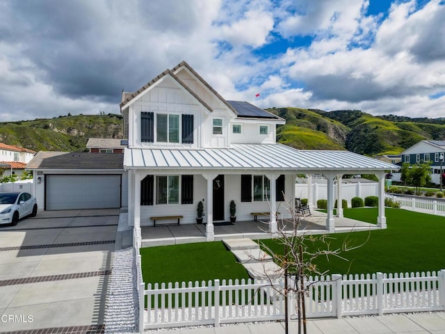 modern inspired farmhouse with a garage, a front lawn, a porch, a fenced front yard, and solar panels