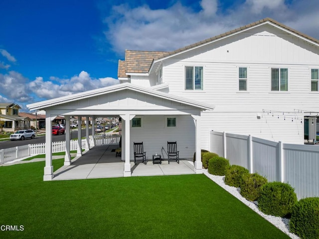 back of property with a lawn, a fenced backyard, board and batten siding, and a patio