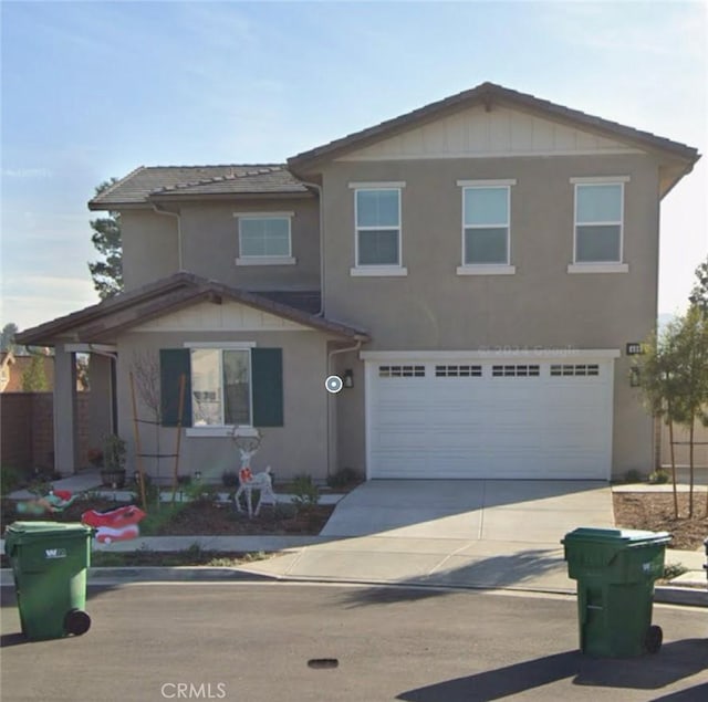 traditional-style house featuring a garage, stucco siding, and concrete driveway