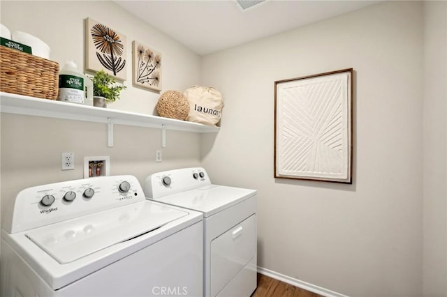 laundry area featuring laundry area, visible vents, wood finished floors, baseboards, and washing machine and clothes dryer