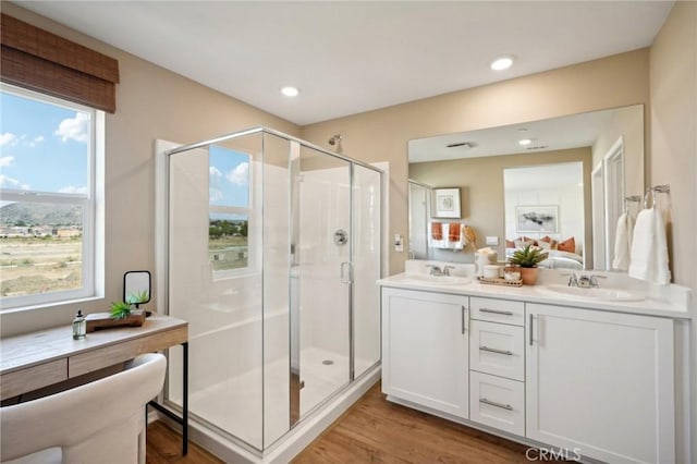 bathroom featuring a sink, a stall shower, wood finished floors, and a healthy amount of sunlight