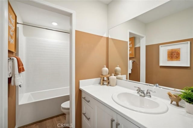 bathroom featuring vanity, wood finished floors, bathtub / shower combination, and toilet