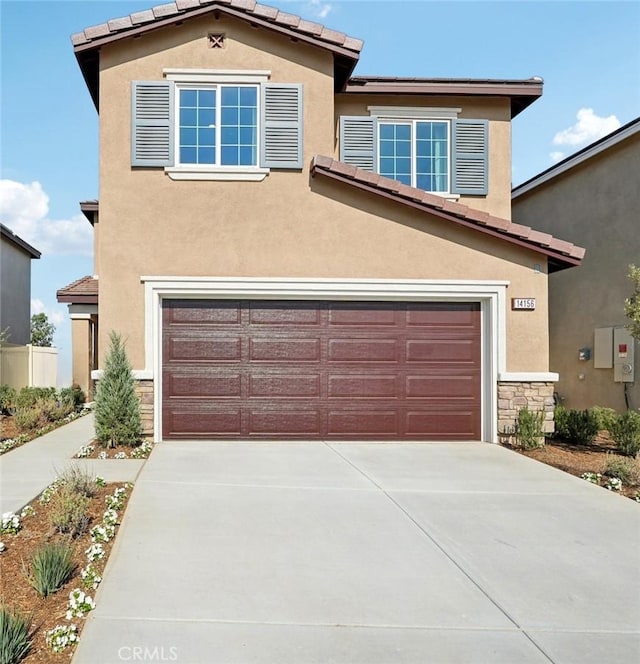 traditional-style home featuring an attached garage, driveway, and stucco siding