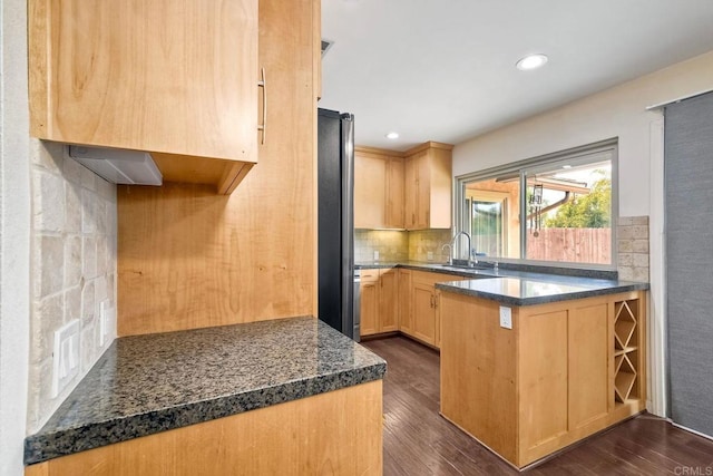 kitchen with a peninsula, light brown cabinetry, tasteful backsplash, and dark wood finished floors