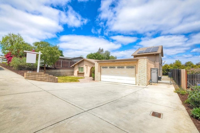 view of front facade with fence, an attached garage, roof mounted solar panels, a gate, and driveway