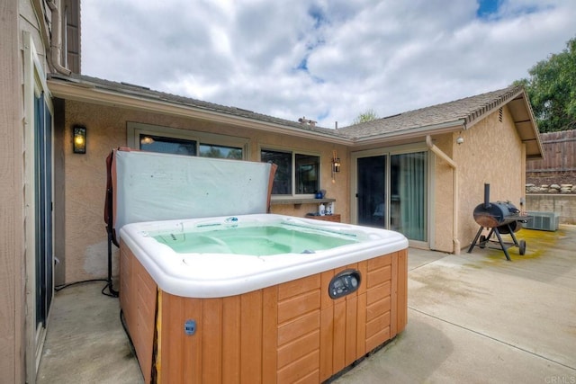 view of patio with central air condition unit, a hot tub, and area for grilling