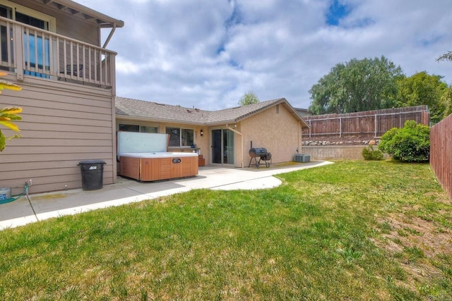 rear view of property with a hot tub, a fenced backyard, central air condition unit, a patio, and a yard