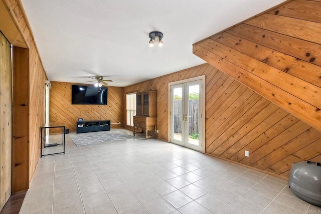 unfurnished living room with wooden walls, ceiling fan, and tile patterned floors
