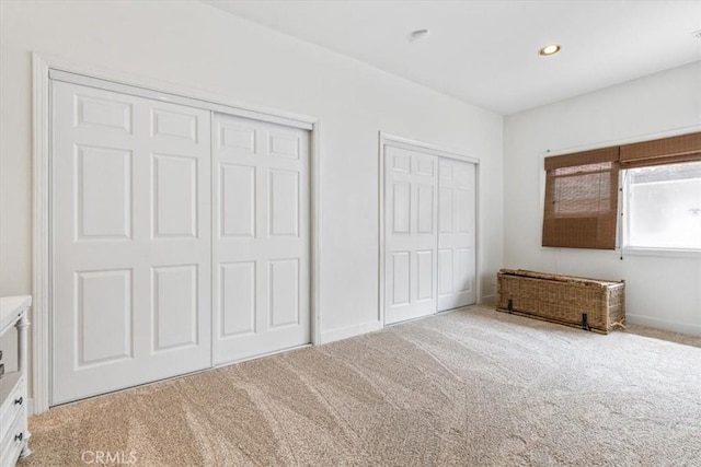 unfurnished bedroom with carpet floors, recessed lighting, and multiple closets