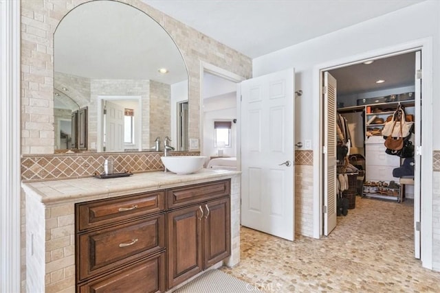 full bathroom featuring a walk in closet, decorative backsplash, vanity, and recessed lighting