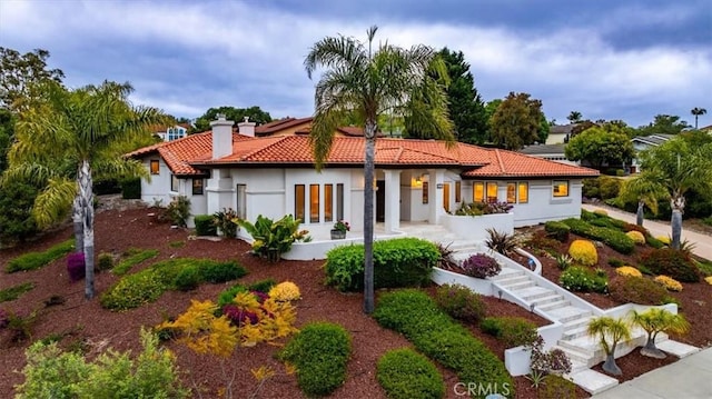 back of property featuring a chimney, stucco siding, and a tile roof