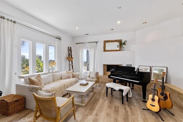living area with recessed lighting, a fireplace, and light wood-type flooring