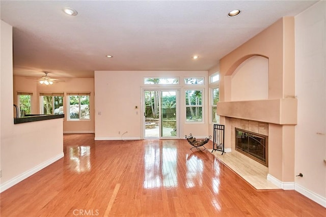 unfurnished living room with a tiled fireplace, baseboards, and a wealth of natural light