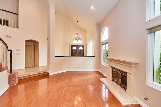 unfurnished living room with stairway, high vaulted ceiling, plenty of natural light, and arched walkways