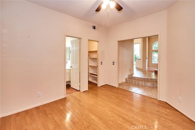 spare room with a ceiling fan, baseboards, visible vents, and light wood-type flooring
