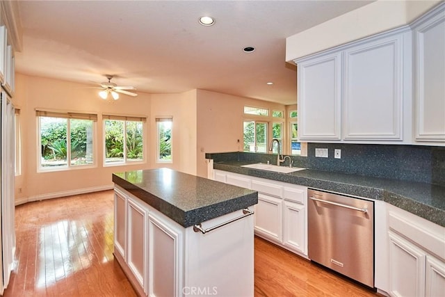 kitchen featuring a center island, stainless steel dishwasher, a sink, light wood-style floors, and recessed lighting