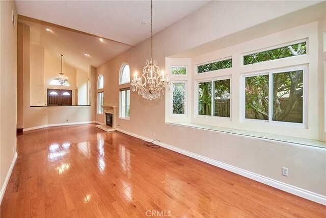 unfurnished dining area featuring baseboards, a chandelier, a healthy amount of sunlight, and high vaulted ceiling