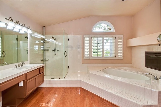 full bathroom with vanity, wood finished floors, a bath, a shower stall, and vaulted ceiling