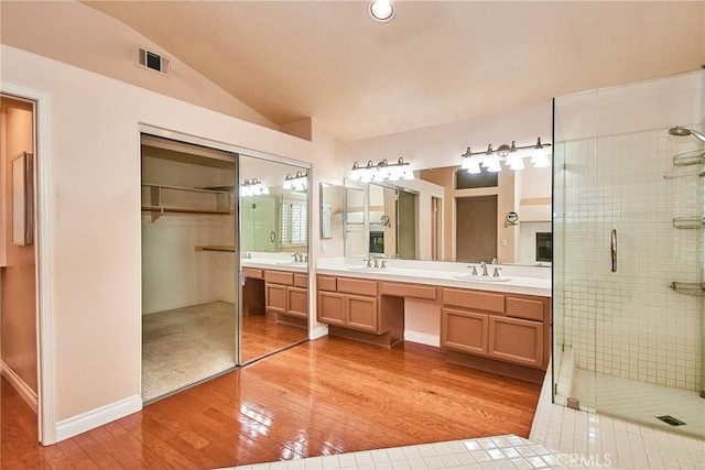 full bathroom featuring vaulted ceiling, wood-type flooring, a stall shower, and visible vents