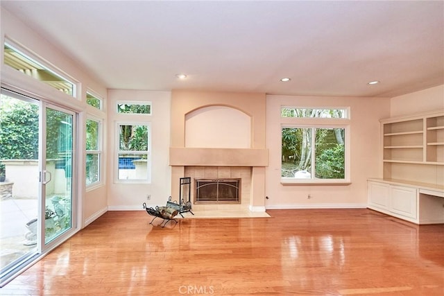 unfurnished living room with recessed lighting, baseboards, wood finished floors, and a tile fireplace