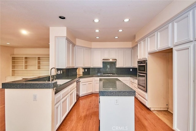 kitchen with appliances with stainless steel finishes, a sink, recessed lighting, light wood-type flooring, and tasteful backsplash
