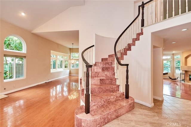stairway with baseboards, high vaulted ceiling, and a healthy amount of sunlight