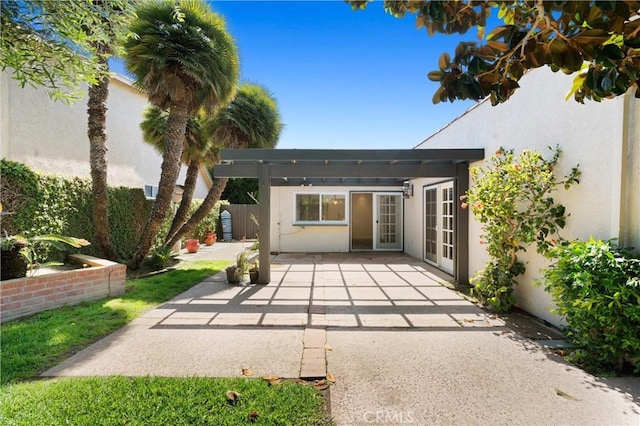 22122 Cape May Ln, Huntington Beach, CA 92646 - view of exterior entry with fence, a pergola, stucco siding, a patio area, and french doors