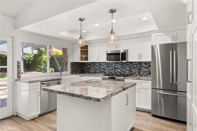 22122 Cape May Ln, Huntington Beach, CA 92646 - kitchen featuring a tray ceiling, white cabinets, stainless steel appliances, and light wood-type flooring