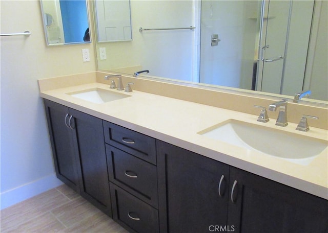 bathroom with double vanity, a sink, an enclosed shower, and wood finished floors