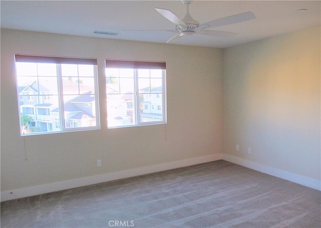 carpeted empty room with baseboards, ceiling fan, and visible vents