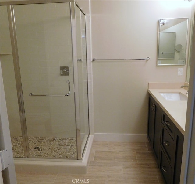 full bathroom with vanity, baseboards, and a stall shower